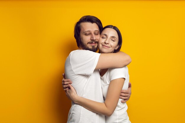 Foto el marido y la esposa en camisetas blancas de pie sobre un fondo amarillo