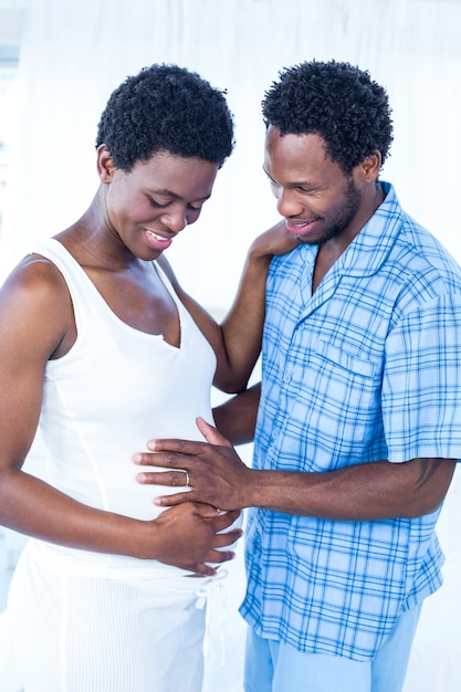 Marido feliz tocando a barriga da mulher grávida em pé