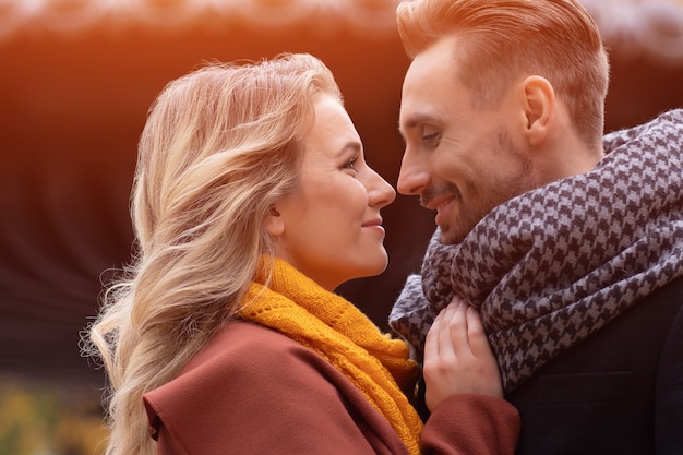 Marido y mujer abrazaron sonrisa mirando el uno al otro en el parque de otoño