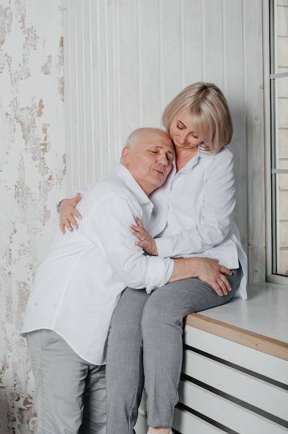 marido y mujer con camisas blancas se abrazan y besan