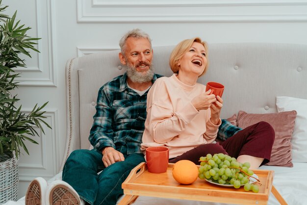 Marido y mujer desayunan en la cama con café y fruta.