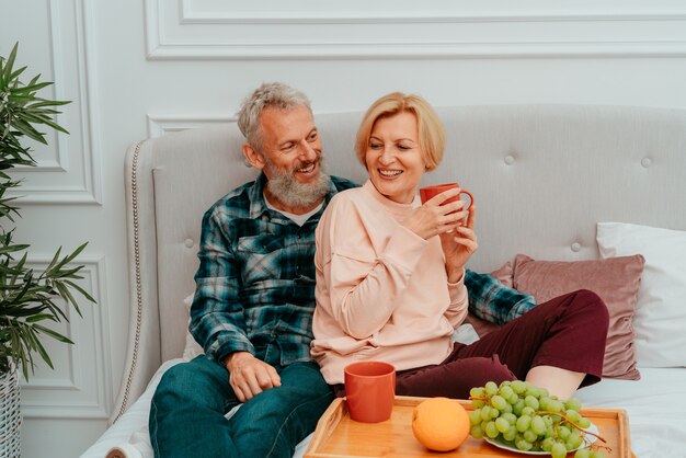 Marido y mujer desayunan en la cama con café y fruta.