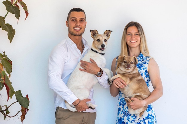 Marido y mujer con dos cachorros sobre un fondo blanco.