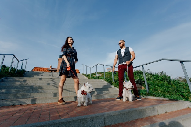 Marido y mujer paseando dos perritos blancos