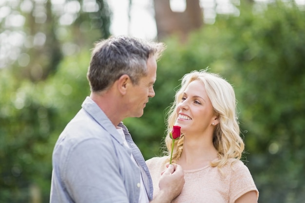 Marido ofreciendo una rosa a su esposa afuera en el bosque