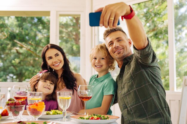 Marido pegando seu smartphone enquanto faz selfie com a família