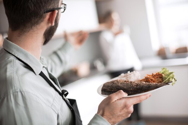 Marido con un plato de cena cocinada de pie en la cocina