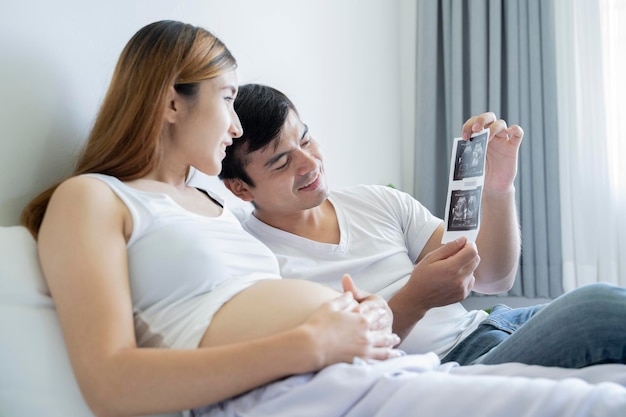 El marido que le sonríe a la mujer embarazada con la ecografía del bebé