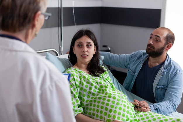 Foto marido sentado ao lado da esposa grávida no hospital