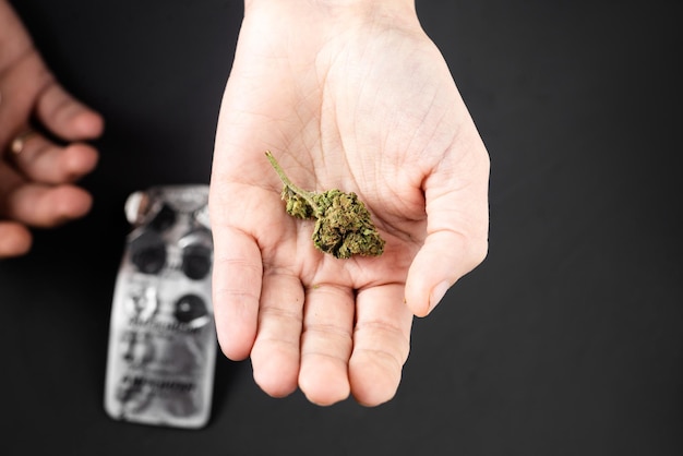 Marihuana-Knospe auf einer weiblichen Hand auf dem Hintergrund von Pillen unscharf Medizinisches Cannabis als Alternative zum Drogenkonzept
