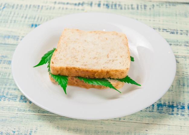 Marihuana und Lebensmittel Ein Sandwich mit Marihuanablättern Die Verwendung von Cannabis bei der Herstellung von Lebensmitteln Das Konzept der Steigerung des Appetits nach dem Konsum von Marihuana