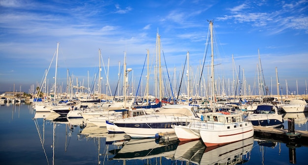 Marina en Larnaca alberga barcos amarrados Chipre Reflejo de barcos cielo azul con fondo de nubes