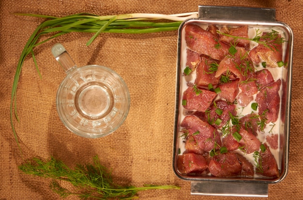 Marinado em carne com leite e verduras em um prato de aço sobre um pano com ervas frescas e uma caneca de cerveja