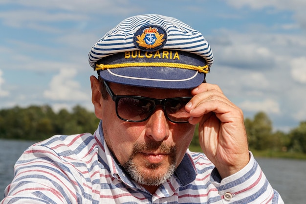 Marinero con gorra en un barco a vela contra el cielo y el agua