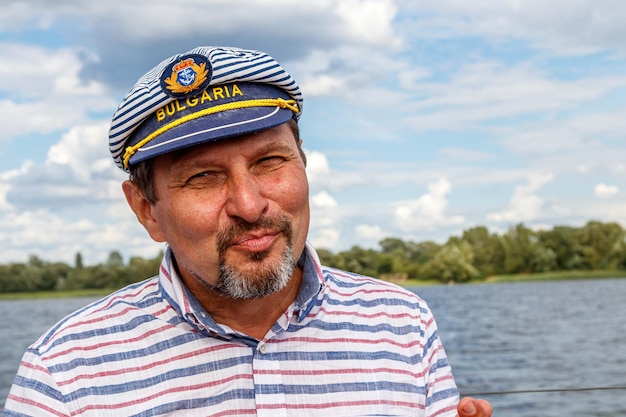 Marinero con gorra en un barco a vela contra el cielo y el agua