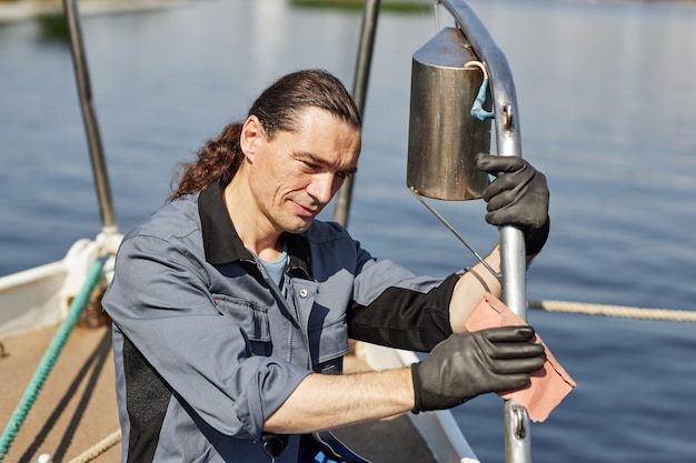 Marinheiro de cabelos compridos sorridente limpando barco com cena de cuidado