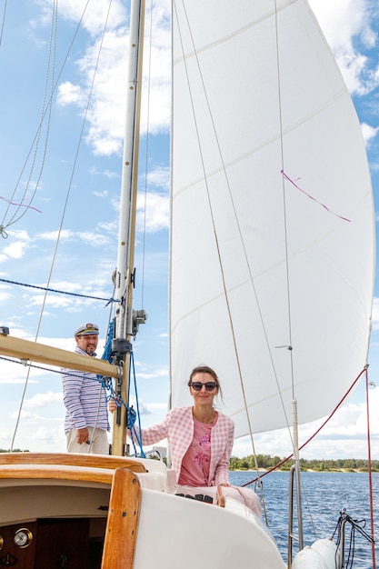 Marinheiro em um boné com uma garota em um barco a vela contra o céu e a água