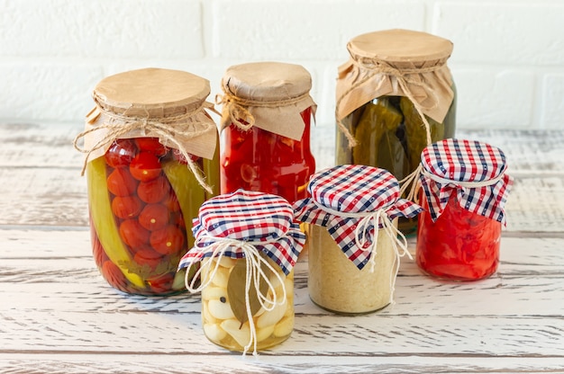 Marinierte Essiggurken Sorte Einmachgläser. Hausgemachte Tomaten, Gurken, Knoblauch, Ingwer und Meerrettichgurken. Fermentiertes Essen.