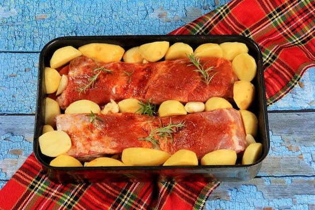 Marinierter frischer Schweinebauch mit Paprika-Rosmarin, Gewürzen und Gemüse in einer Metallpfanne