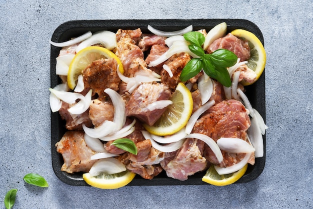 Marinierter Schaschlik mit Zwiebeln und Zitrone. Schweinefleisch mit Gewürzen auf einem Tablett.