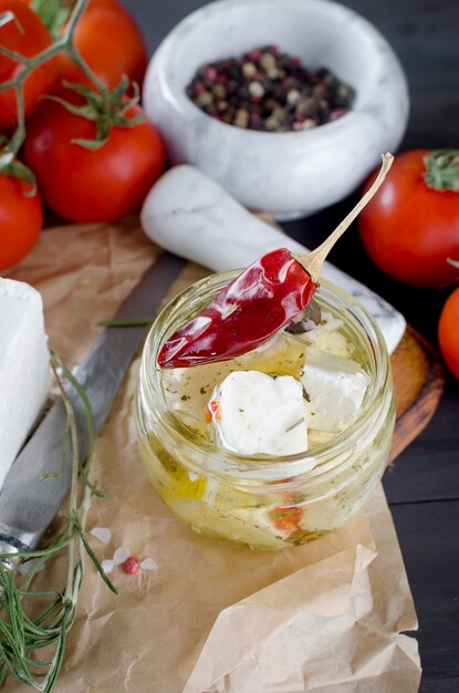 Marinierter würziger Feta in einem Glas und Gemüse für Salat.