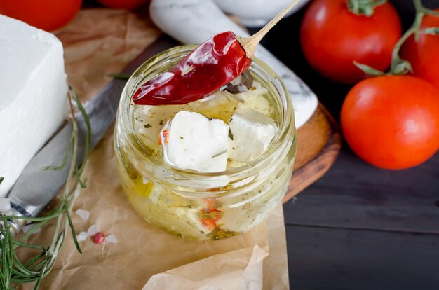 Marinierter würziger Feta in einem Glas und Gemüse für Salat.