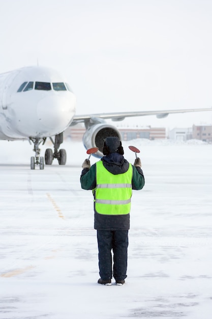 El mariscal del aeropuerto se encuentra con el avión que se estaciona en un clima frío de invierno