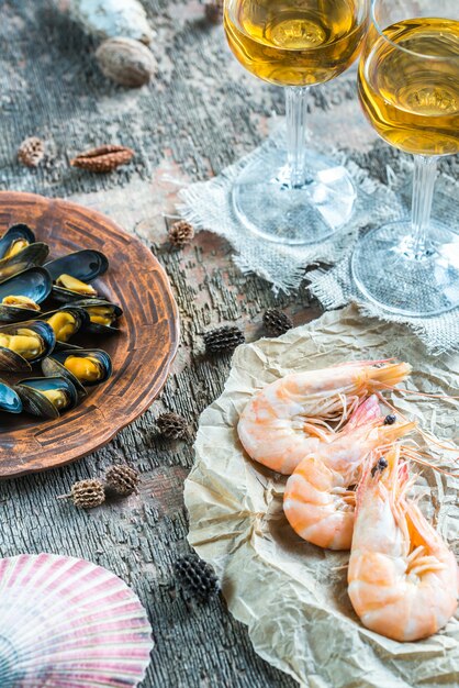 Mariscos con dos copas de vino blanco en la mesa de madera