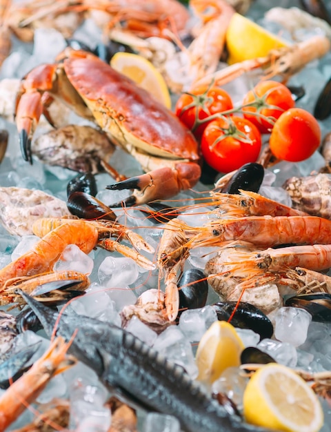 Foto mariscos en hielo. cangrejos, esturiones, crustáceos, camarones, rapana, dorado, sobre hielo blanco.