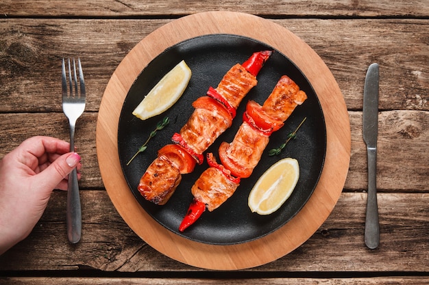 Mariscos japoneses. Salmón a la plancha en brochetas con ají y tomate, decorado con limón. Vista superior.