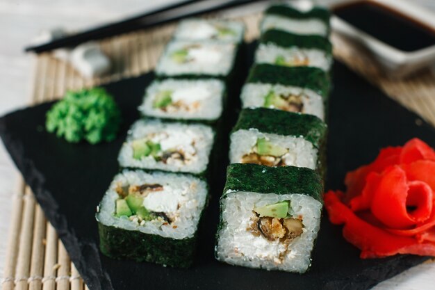 Mariscos japoneses saludables. Delicioso juego de sushi maki servido en pizarra negra, primer plano. Foto de menú de restaurante de lujo.