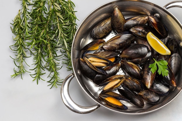 Foto mariscos mejillones en sartén romero y limón en la mesa