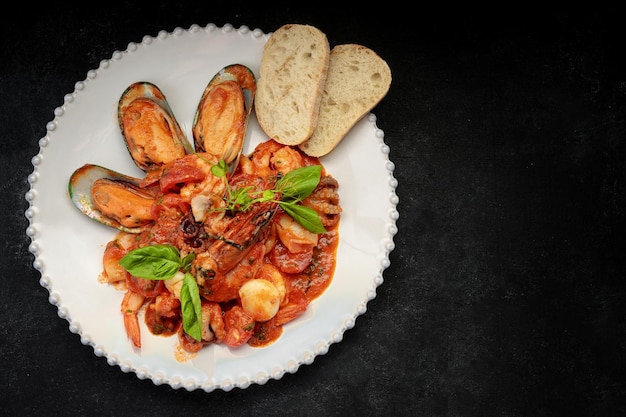 Mariscos salteados en un plato blanco con tostadas en un fondo oscuro