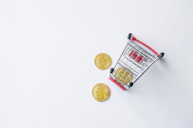 Market down concepto golden bitcoin en carrito de compras en la vista superior de fondo de mesa blanca