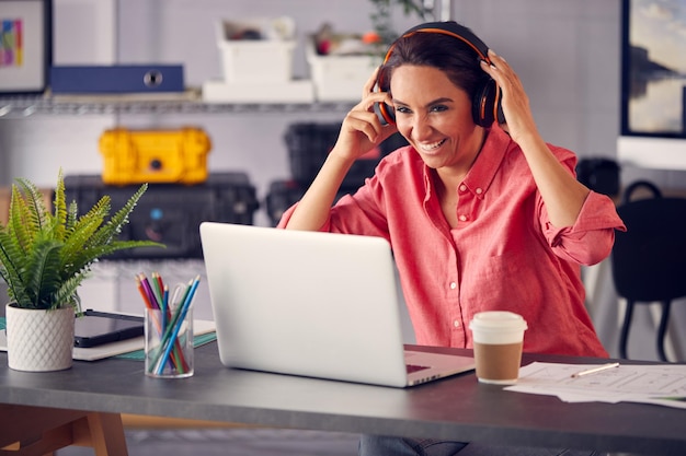 Marketing de publicidade feminina ou design criativo com fones de ouvido sem fio na mesa trabalhando no laptop