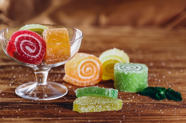 Marmelada de frutas multicoloridas está sobre uma mesa de madeira