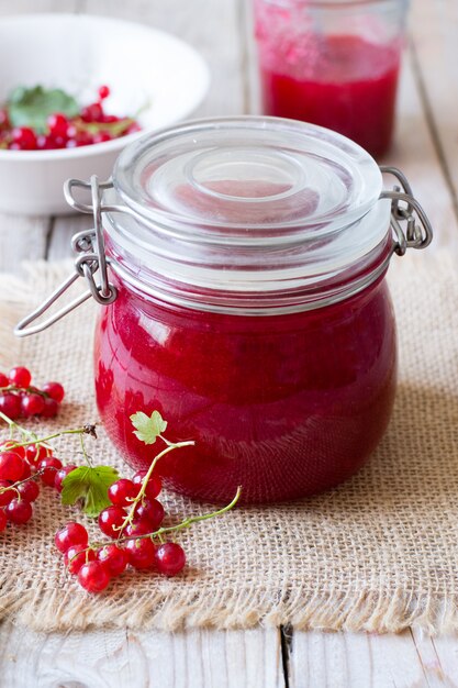 Marmelade der roten Johannisbeere im Glas auf Holztisch