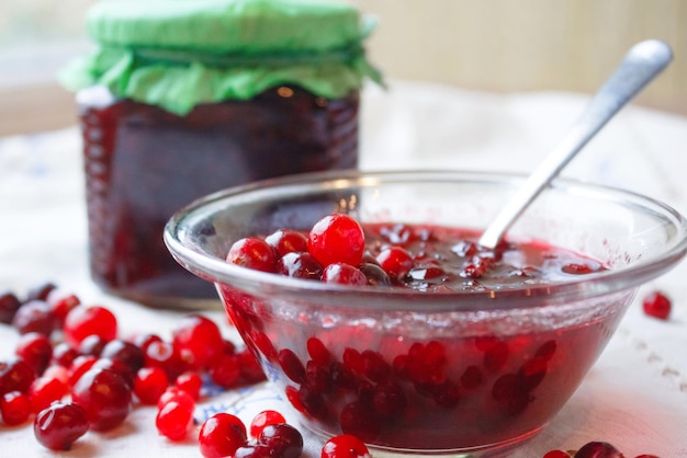 Marmelade in einer Schüssel, Beeren und ein Glas Marmelade auf einer weißen Tischdecke