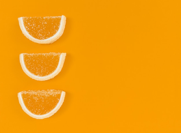 Foto marmelade orangenscheiben in zucker auf orangefarbenem hintergrund mit kopierraum.