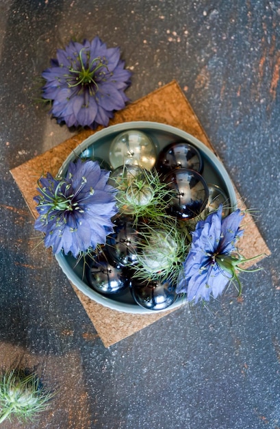 Mármoles de vidrio y flores de nigella damascena en un cuenco de cerámica azul