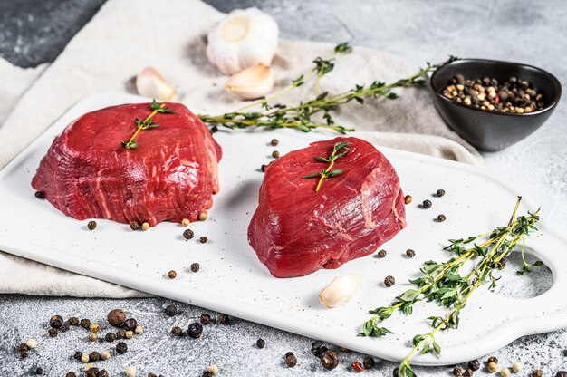 Marmor-Rinderfilet. Rohes Filet Mignon Steak auf einem weißen Schneidebrett. Grauer Hintergrund. Draufsicht