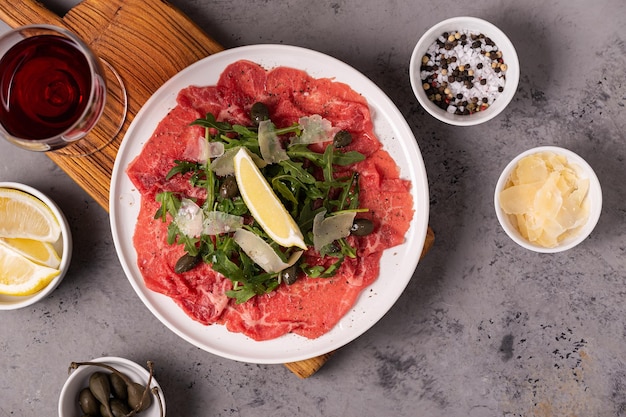 Marmoriertes Rindercarpaccio mit Rucola, Kapern, Zitrone und Parmesankäse