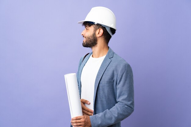 Marokkanischer Mann des jungen Architekten mit Helm und gehaltenen Blaupausen isoliert