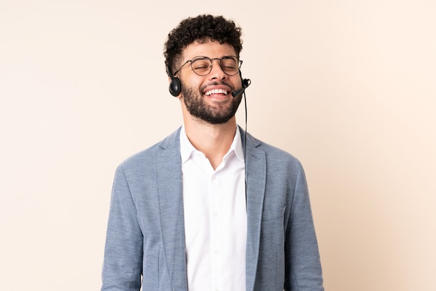 Marokkanischer Mann des Telemarketers, der mit einem Headset arbeitet, das auf beige Wandlachen lokalisiert wird