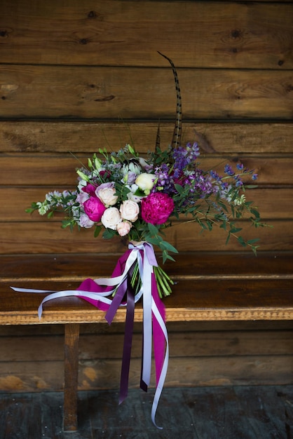 Foto marsala-hochzeitsblumenstrauß mit bändern auf hölzernem hintergrund