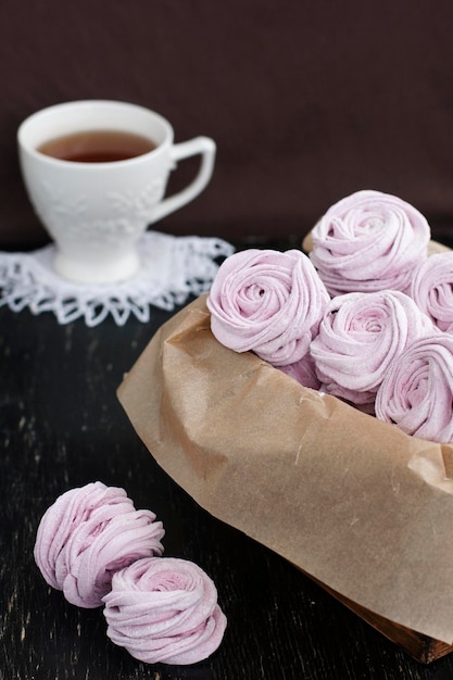 Marshmallow artesanal baga, xícara de chá e lenços um branco sobre um fundo preto de madeira vintage.