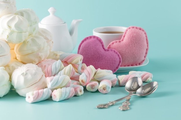 Foto marshmallow auf aquamarinhintergrund mit tasse tee a² spielzeugherzen