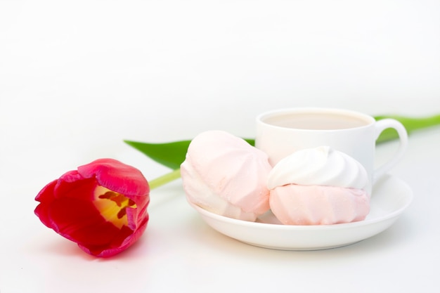 Marshmallow, chá ou café com leite e uma flor de tulipa. numa superfície clara Manhã romântica de primavera. café da manhã delicado, café da manhã na cama. para o amado. Surpresa.