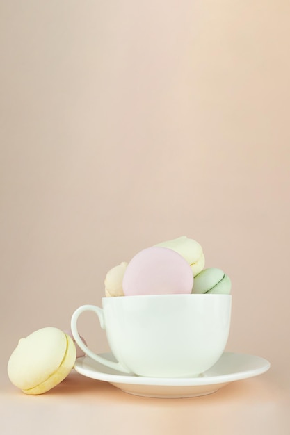 Marshmallow colorido parece macarons franceses de fundo em caneca de xícara de café branco de porcelana fechar