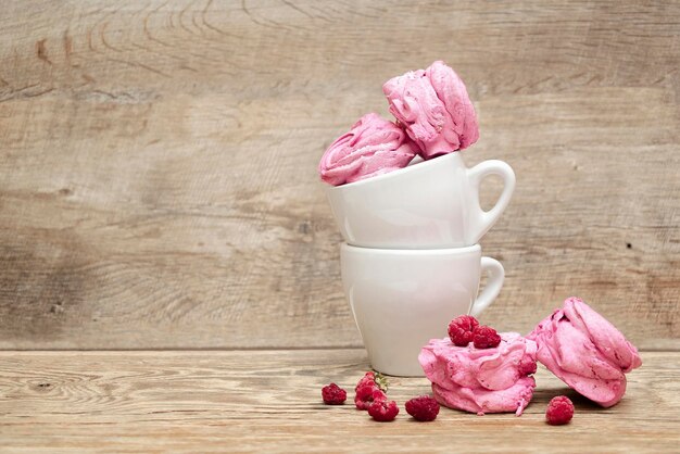 Marshmallow rosa doce em copo com framboesa fresca com espaço de cópia em fundo de madeira conceito de comida do Dia dos Namorados